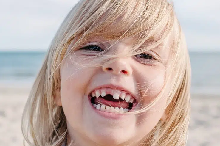 Eines kleines Kind lächelt am Stand während des Zahndurchbruches